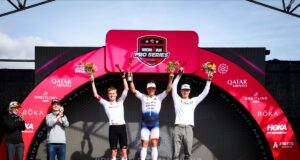 Three men stand on a podium with arms in the air in celebration