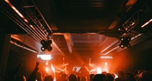 People in a night club with lights glowing orange on a stage