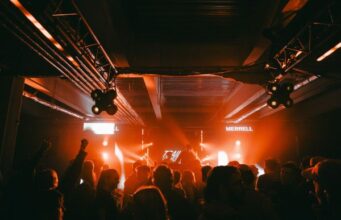 Merrell hosts club night powered by trail runners People in a night club with lights glowing orange on a stage