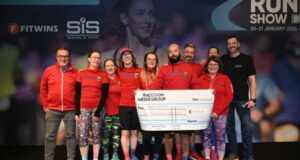 A group of people wearing red tops hold a large cheque