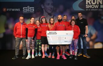 A group of people wearing red tops hold a large cheque