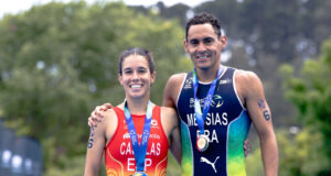 A woman and man in tri suits and with medals around their necks pose for the camera together, smiling.