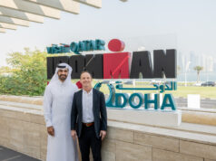 Doha to Host First-Ever IRONMAN 70.3 Triathlon in Qatar Two men stand in front of IRONMAN Doha sign. Man on right is dressed in black suit, man on left is wearing a white thawb
