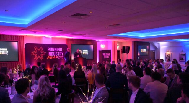 Running Industry Awards Winners Phooto of a room full of people dressed smartly, at round tables, all watching a speaker on a stage