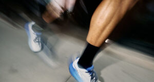 Close up of blurred runners legs wearing white shoes with blue trim