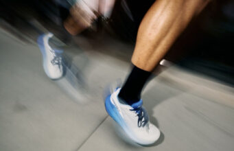 Close up of blurred runners legs wearing white shoes with blue trim