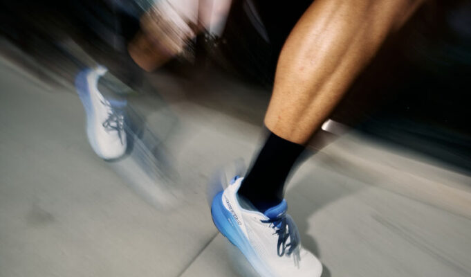 Close up of blurred runners legs wearing white shoes with blue trim