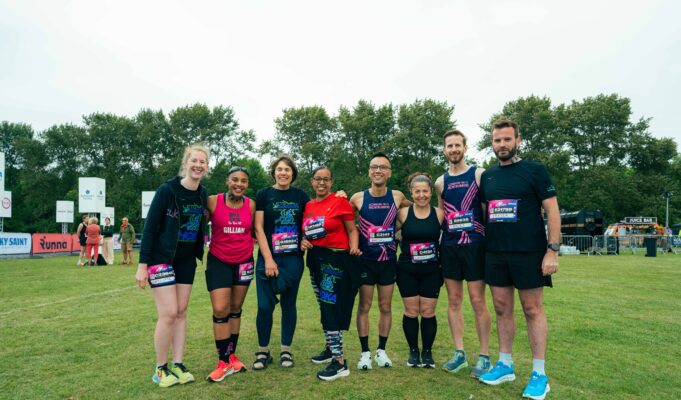 A group of 8 male and female runners wearing race numbers pose for a photo