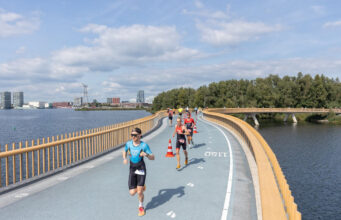 Challenge Almere-Amsterdam launches marathon Triathletes run along a road bridge over a lake