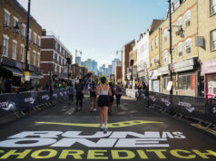 London’s freshest half marathon lands this September View of a road race. RUN AS ONE SHOREDITCH is painted on the road in the foreground.