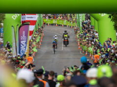 A motorbike follows two triathletes on bikes