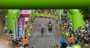 A motorbike follows two triathletes on bikes