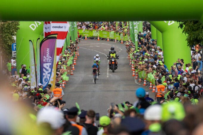 A motorbike follows two triathletes on bikes