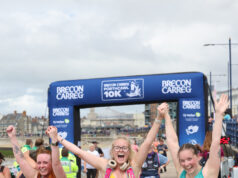 Brecon Carreg continues as Porthcawl 10K sponsor Three young women hold their arms aloft, all joined hands, as they cross the finish line.