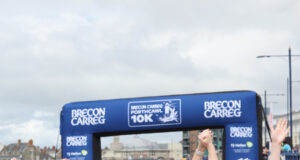 Three young women hold their arms aloft, all joined hands, as they cross the finish line.
