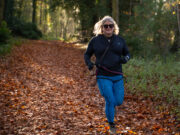 New trail running retreats for midlife women A blonde woman runs through a forest