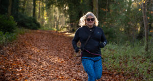 A blonde woman runs through a forest