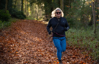 New trail running retreats for midlife women A blonde woman runs through a forest