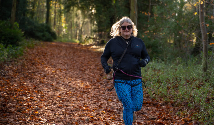 A blonde woman runs through a forest