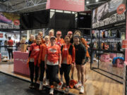 A group of women mostly wearing orange pose at the national running show