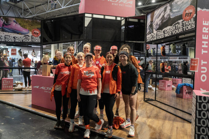 A group of women mostly wearing orange pose at the national running show
