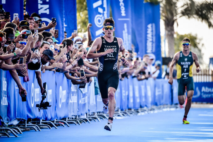 World Triathlon Two male triathletes race down a blue carpet lined with fans
