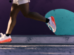 Legs of a runner. They're wearing white and orange cushioned running shoes.