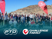 A group of people pose in front of a rocky backdrop with two red flags