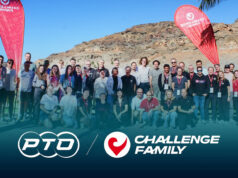 A group of people pose in front of a rocky backdrop with two red flags
