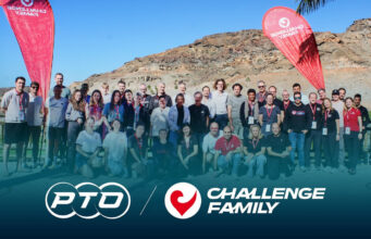 A group of people pose in front of a rocky backdrop with two red flags