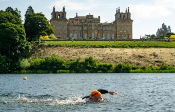 Supertri Blenheim Palace gears up for 2026 A swimmer wearing an orange swim hat swims in a lake past Blenheim Palace