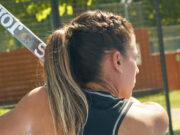 Joma strengthens its commitment to sustainability with new materials Woman with braided brown hair has back to the camera, holding a padel board.