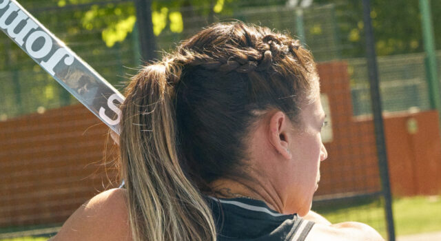 Joma strengthens its commitment to sustainability with new materials Woman with braided brown hair has back to the camera, holding a padel board.