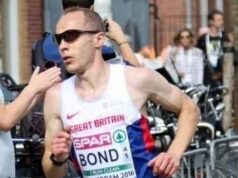 Male runner in GB vest has short cropped dark hair and wears dark sunglasses.