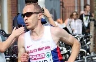 Male runner in GB vest has short cropped dark hair and wears dark sunglasses.