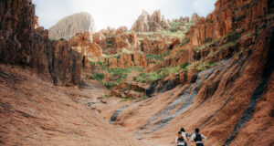 Three runners run away from the camera in a small rocky valley