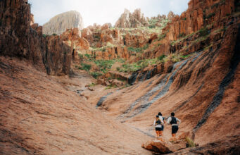 Three runners run away from the camera in a small rocky valley