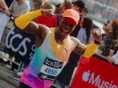 Man in brightly coloured orange/green/purple PUMA kit flexes his biceps at the camera as he runs past, smiling