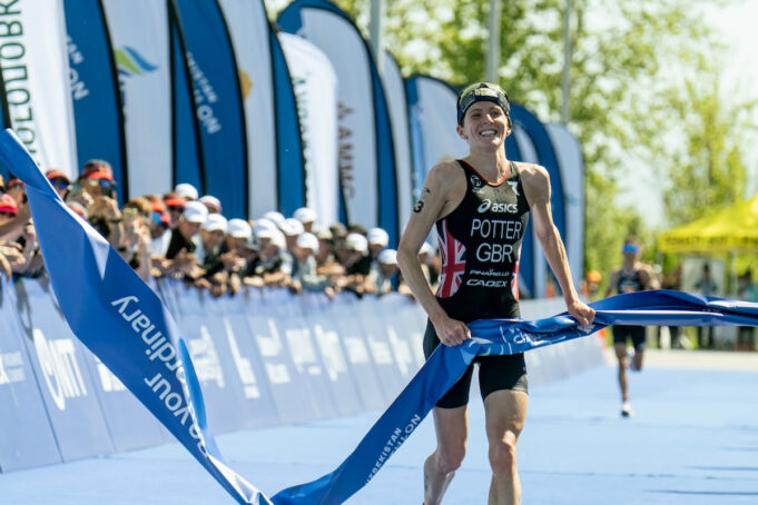 Beth Potter WTCS Female triathlete has a smile on her face as she jogs through the finishing tape