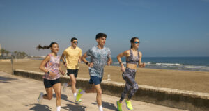 Two men and two women n colourful kit run by the sea