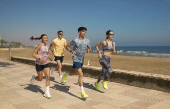 Two men and two women n colourful kit run by the sea