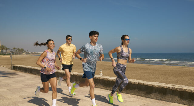 Two men and two women n colourful kit run by the sea