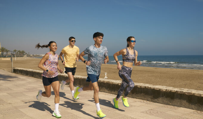 Two men and two women n colourful kit run by the sea