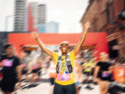 London’s new half marathon is open for entry A runner in yellow top put her hands iin the air in a road race. The background is blurred but there is a red gantry behind.