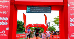a family of two adults and two children run under a red finish gantry