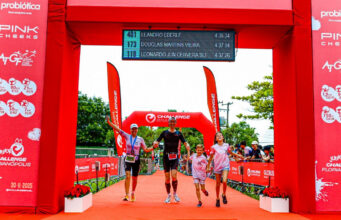a family of two adults and two children run under a red finish gantry