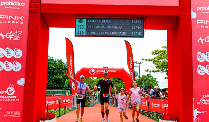 a family of two adults and two children run under a red finish gantry