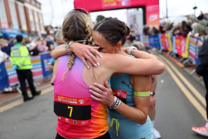Barry Island 10k Two female runners hug beyond the finish gantry