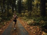 A topless male runner on a track through a forest