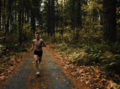 A topless male runner on a track through a forest